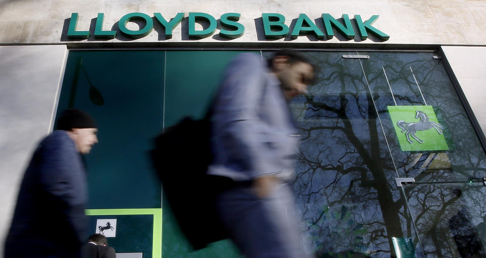 People walk past a branch of Lloyds Bank in London, Thursday, Jan. 28, 2016. Britain's Chancellor George Osborne has announced that the sale of the government's stake in Lloyds Banking Group will be delayed. (AP Photo/Kirsty Wigglesworth)