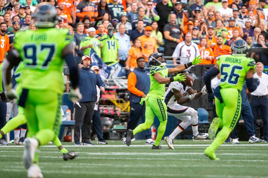 Denver Broncos wide receiver Jerry Jeudy (10) catches a pass from quarterback Russell Wilson (3) as Seattle Seahawks cornerback Coby Bryant (8) defends during the second quarter of an NFL game on Monday, Sept. 12, 2022, at Lumen Field in Seattle. Jeudy would score on the play.