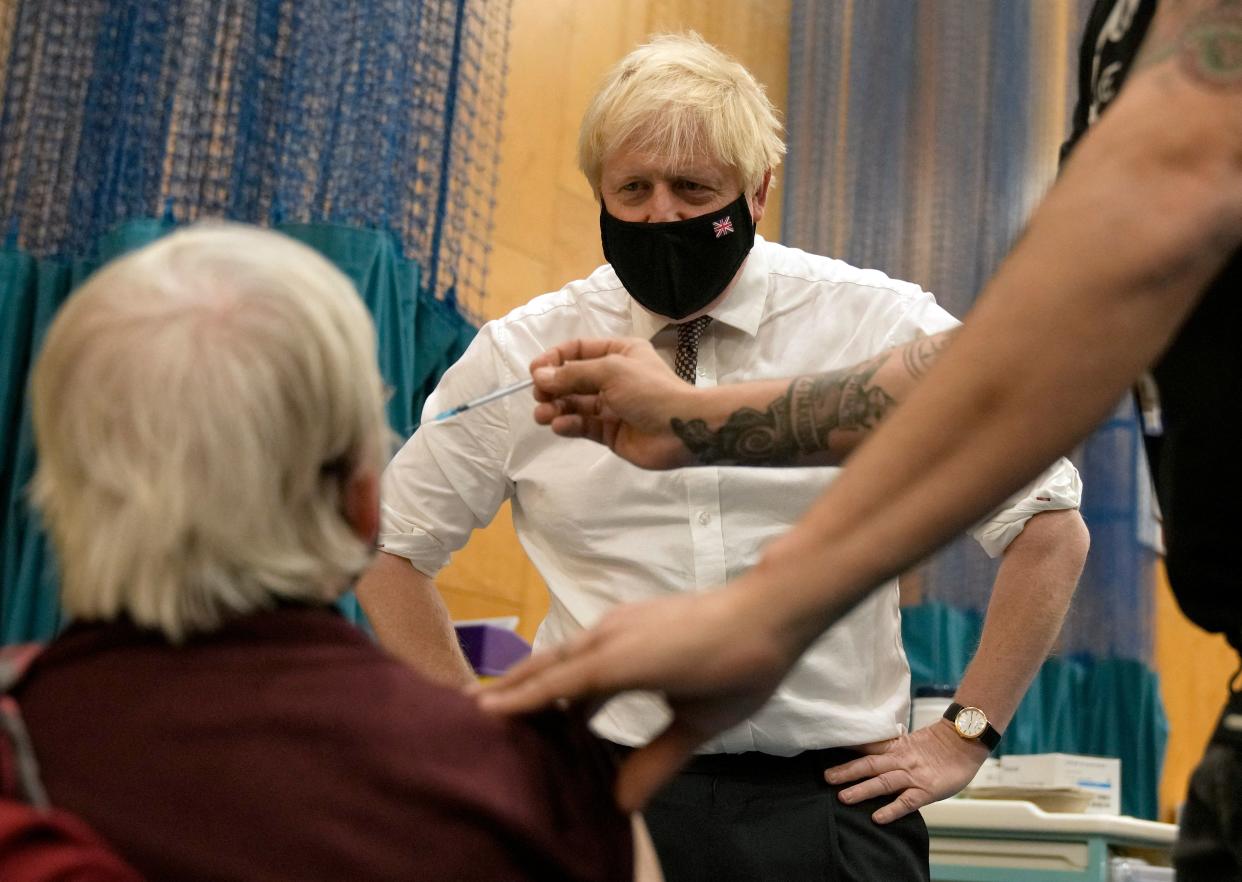 British Prime Minister Boris Johnson watches as 88-year-old Nitza Sarner receives a Pfizer-BioNTech  booster vaccination as he visits a Covid-19 vaccination centre at Little Venice Sports Centre in London on October 22, 2021. - Daily virus cases in the UK on October 22 soared to over 50,000 a day for the first time since July but the government again resisted calls to reimpose restrictions. The UK has administered two vaccine doses to 79 percent of those aged 12 and over and the number of hospitalisations remains relatively low. It is pushing for all those not inoculated to get the vaccine and urging the over-50s and clinically vulnerable to take up the offer of a third booster vaccine as well as get flu jabs. (Photo by Matt Dunham / POOL / AFP) (Photo by MATT DUNHAM/POOL/AFP via Getty Images)