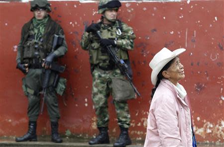 Soldiers stand guard as a woman walks past during a congressional election in Toribio in Cauca province March 9, 2014. REUTERS/Jaime Saldarriaga