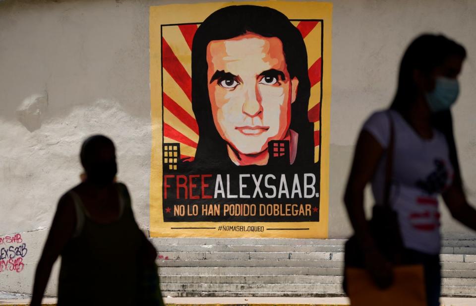 Pedestrians walk near a poster asking for the freedom of Colombian businessman and Venezuelan special envoy Alex Saab, in Caracas, Venezuela, 9 September 2021. (AP)
