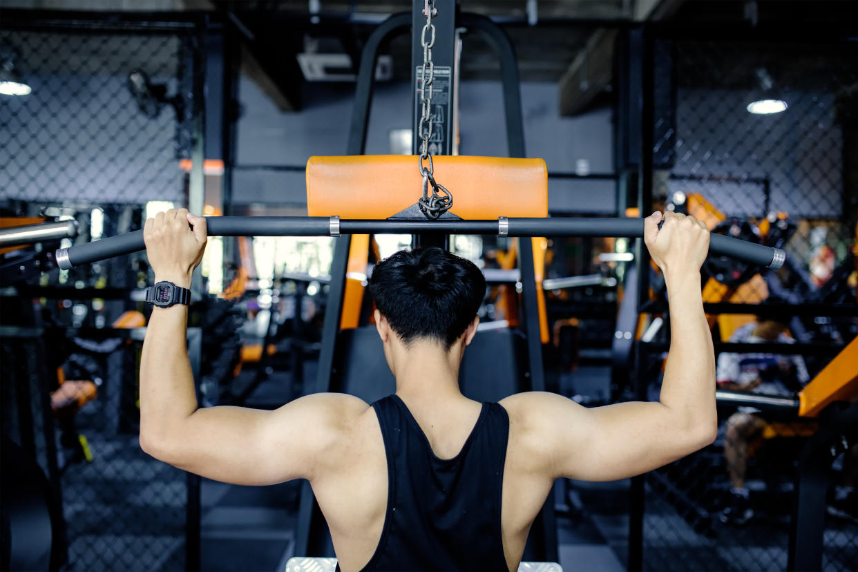 Muscular bodybuilder guy doing exercises with dumbbells in gym