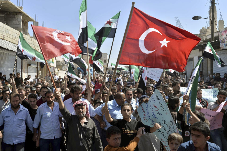 FILE - This September 14, 2018 file photo, protesters wave revolutionary Syrian and Turkish flags as they attend a demonstration against the Syrian government offensive in Idlib, in Maarat al-Numan, south of Idlib, Syria. After eight months of relative calm, Idlib is once again a theater for bloody military operations as Syrian government troops, backed by Russia, push their way into the rebel-held enclave in a widening offensive. The violence in May 2019 threatens to completely unravel a crumbling cease-fire agreement reached between Turkey and Russia last September. (Ugur Can/DHA via AP, File)