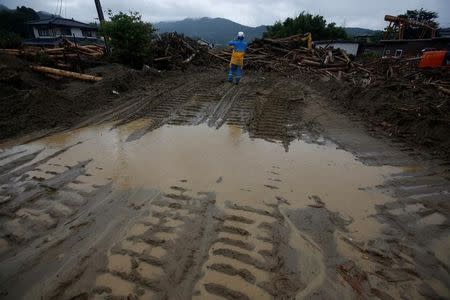 A police officer stands next to debris swept away by heavy rain in Asakura, Fukuoka Prefecture, Japan July 9, 2017. REUTERS/Issei Kato