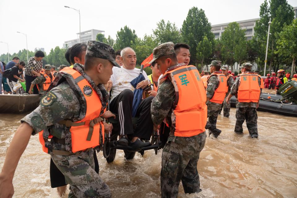 Rescuers help to evacuate a patient across floodwaters. (Source: Getty)