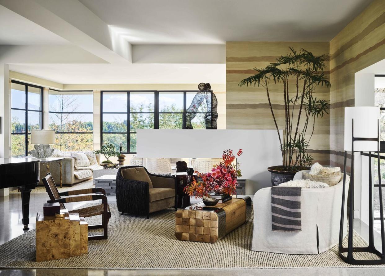 huge windows in the corner of the room let in natural light and the room is decorateed with mostly warm neutral colors