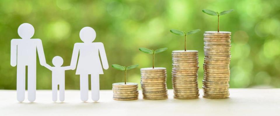 Family members next to coins, sprouting plants, on a table.