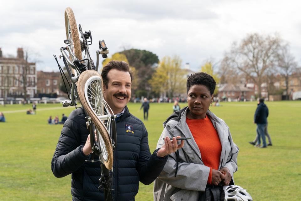 Ted holding a broken bike and talking with Sharon next to him