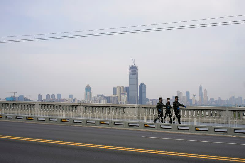 Paramilitary officers wearing face masks walk on a bridge in Wuhan