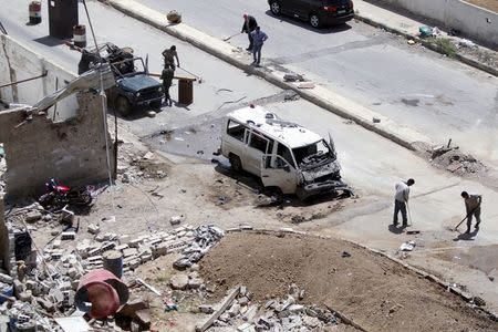 Workers clean a street at the site of a car bomb on the outskirts of the Sayeda Zeinab district south of Damascus, Syria, April 25, 2016. REUTERS/Omar Sanadiki