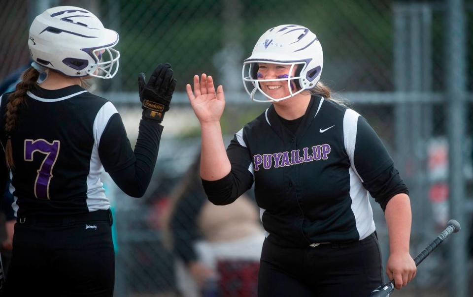 Puyallup designated hitter Taryn Takayoshi is welcomed to the dugout by teammate Sam Bland after scoring a run in the Vikings’ fastpitch game against the Sumner Spartans at Puyallup High School in Puyallup, Washington, on Wednesday, April 27, 2022.