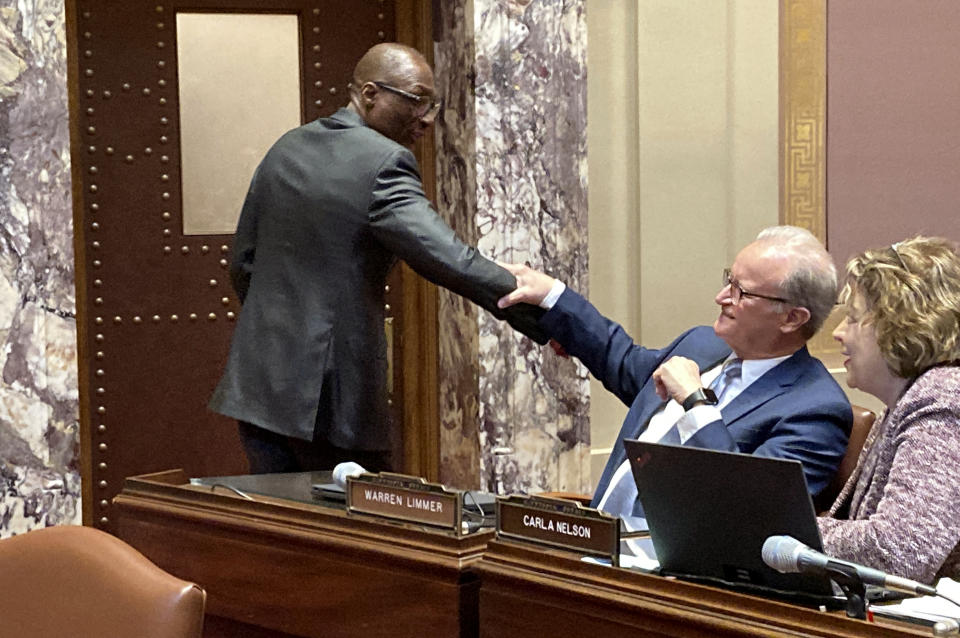 Minnesota Senate President Bobby Joe Champion, left, a Democrat from Minneapolis, and Sen. Warren Limmer, a Republican from Maple Grove, joke with each other on the floor of the Minnesota Senate on Tuesday, Feb. 21, 2023, during a break in the debate over Champion's bill to restore voting rights to felons when they get out of prison before they complete their parole, which Limmer opposes. (AP Photo/Steve Karnowski)