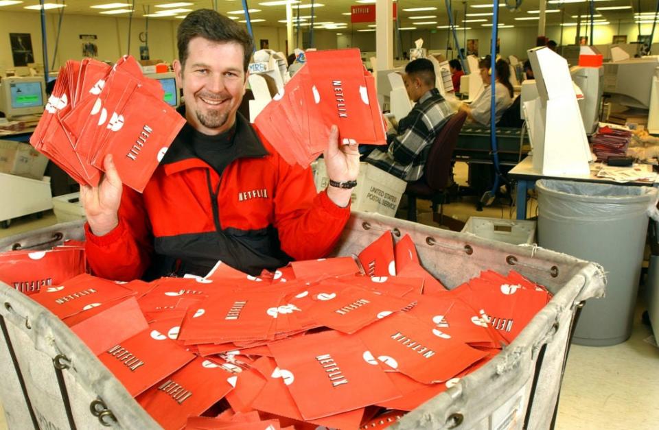 Reed Hastings holding Netflix envelopes at a distribution center