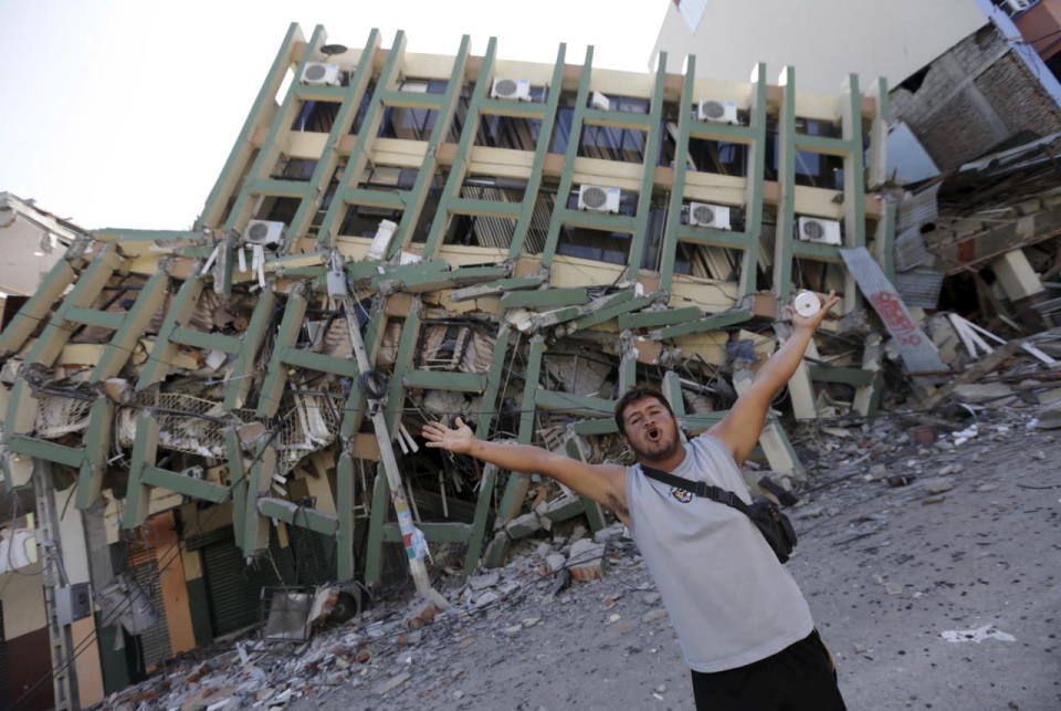 A resident gestures next to a collapsed building 