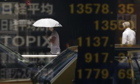 People are reflected on a stock quotation board displaying Japan's Nikkei average (top) and other markets' indices outside a brokerage in Tokyo August 16, 2013.REUTERS/Toru Hanai