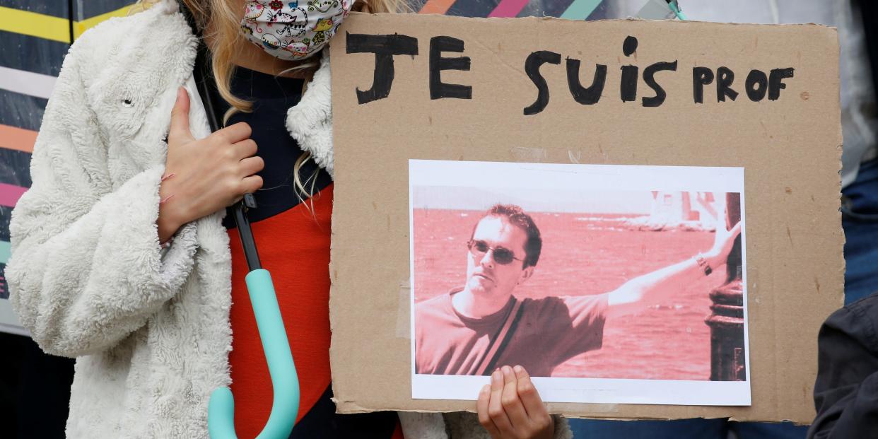 A girl holds a banner with a picture of Samuel Paty, the French teacher who was beheaded on the streets of the Paris suburb of Conflans St Honorine, during a tribute at the Place de la Republique, in Lille, France, October 18, 2020. REUTERS/Pascal Rossignol NO RESALES. NO ARCHIVES.