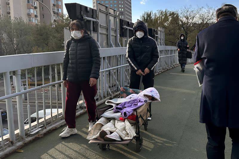Man pushes a child in a camping cart on an overpass near a children's hospital in Beijing