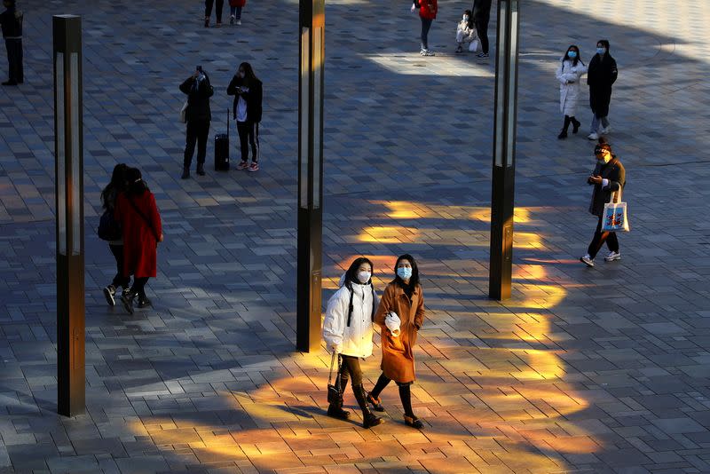 People wearing masks to prevent the spread of the coronavirus disease (COVID-19) walk at a shopping complex in Beijing