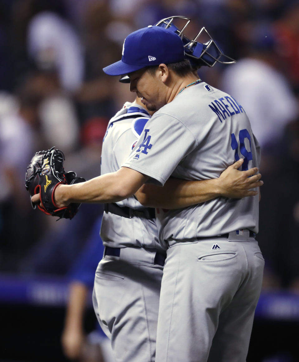 Los Angeles Dodgers relief pitcher Kenta Maeda, front, hugs catcher Austin Barnes after Maeda struck out Colorado Rockies third baseman Nolan Arenado for the final out of a baseball game Friday, Sept. 7, 2018, in Denver. The Dodgers won 4-2. (AP Photo/David Zalubowski)