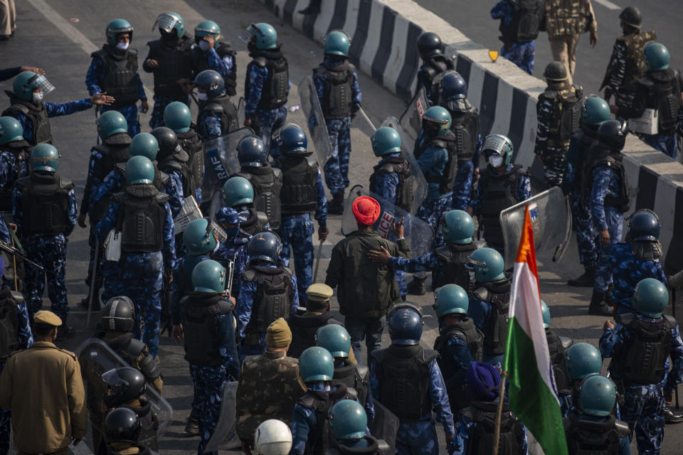 A protesting farmer, wearing orange turban, is let go by riot police as they march to the capital breaking police barricades during India's Republic Day celebrations in New Delhi, India, Tuesday, Jan.26, 2021. Tens of thousands of farmers drove a convoy of tractors into the Indian capital as the nation celebrated Republic Day on Tuesday in the backdrop of agricultural protests that have grown into a rebellion and rattled the government. (AP Photo/Altaf Qadri)