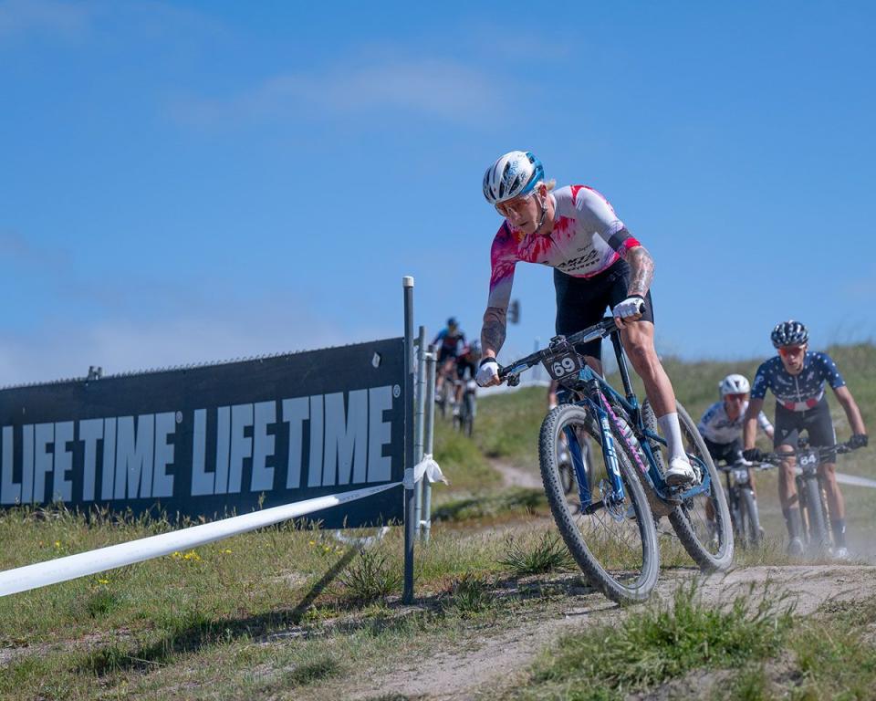 a man riding a bike on a trail with other people behind him