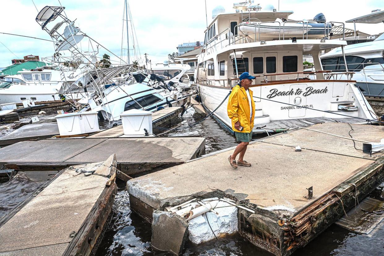 A man inspects damage to a marina as boats are partially submerged in the aftermath of Hurricane Ian in Fort Myers, Florida, on Sept. 29, 2022.