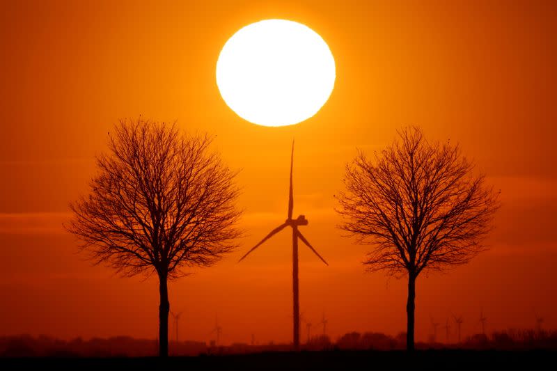 Power-generating windmill turbines are seen during sunset in Bourlon