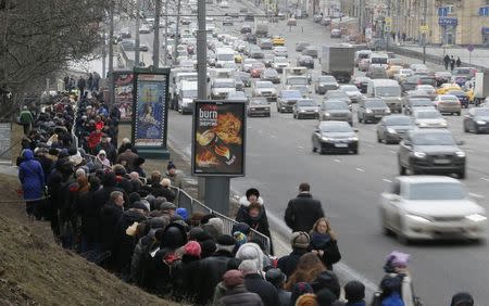 People stand in line to attend a memorial service before the funeral of Russian leading opposition figure Boris Nemtsov, with vehicles driving nearby, in Moscow, March 3, 2015. REUTERS/Maxim Shemetov