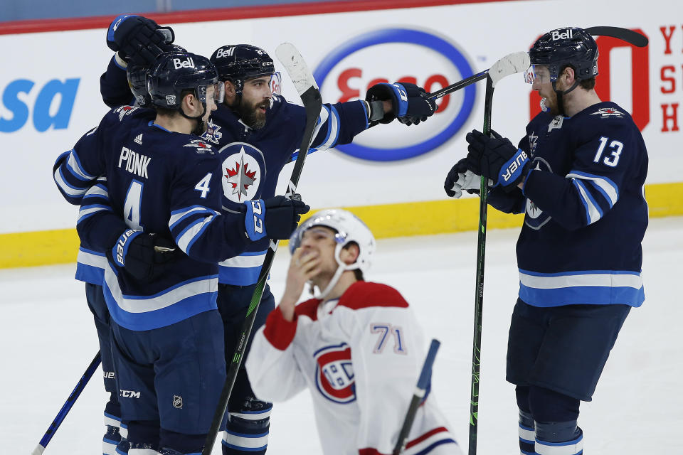 Winnipeg Jets' Neal Pionk (4), Nikolaj Ehlers (27), Mathieu Perreault (85) and Pierre-Luc Dubois (13) celebrate Ehlers' goal as Montreal Canadiens' Jake Evans (71) skates past during the second period of an NHL hockey game Saturday, Feb. 27, 2021, in Winnipeg, Manitoba. (John Woods/The Canadian Press via AP)