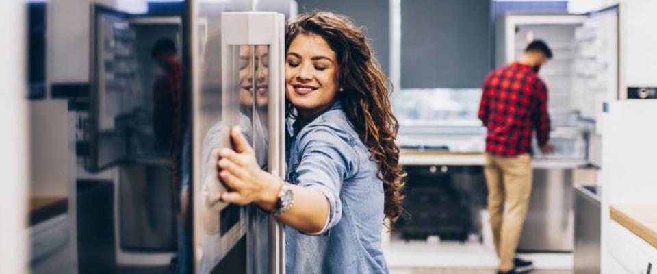 A woman hugging a refrigerator while shopping