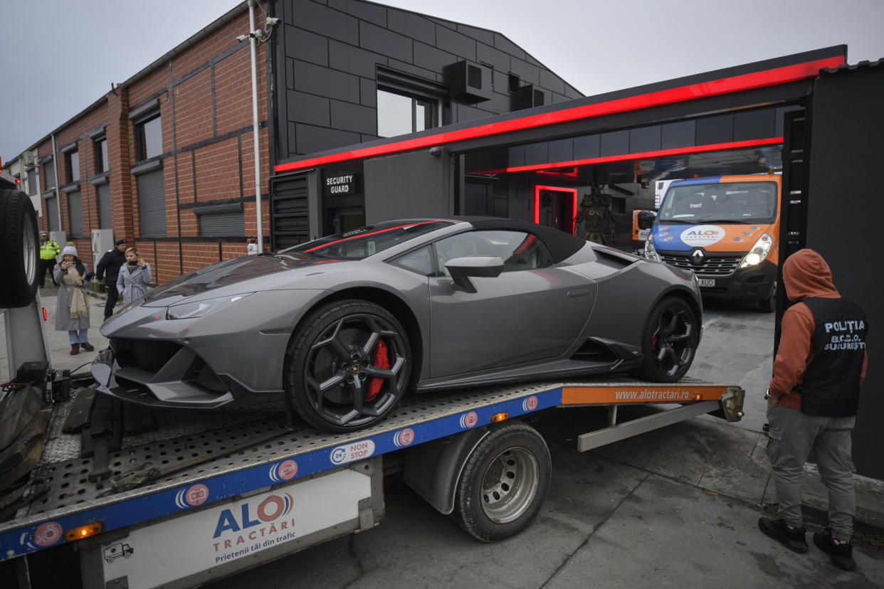 A police officer looks on as a luxury vehicle which was seized in a case against media influencer Andrew Tate, is towed away, on the outskirts of Bucharest, Romania, Saturday, Jan. 14, 2023. Prosecutors seized several luxury vehicles after Tate lost a second appeal this week at a Bucharest court, where he challenged the seizure of assets in the late December raids, including properties, land, and a fleet of luxury cars. More than 10 properties and land owned by companies registered to the Tate brothers have also been seized so far. (AP Photo/Alexandru Dobre)