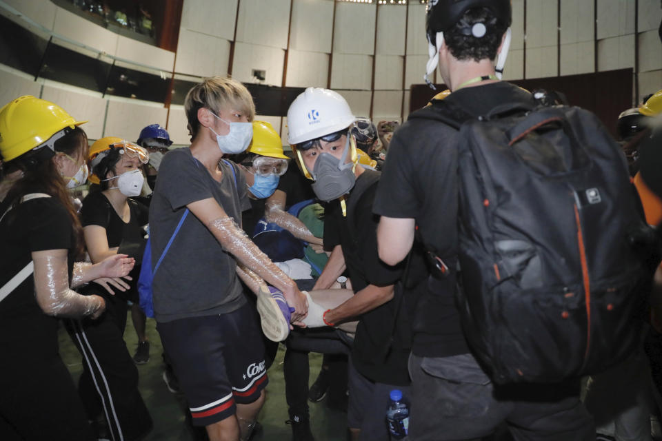 Protesters try to drag out a fellow protester who wanted to stay and fight with the police from the meeting hall of the Legislative Council in Hong Kong, during the early hours of Tuesday, July 2, 2019. Protesters in Hong Kong took over the legislature's main building Friday night, tearing down portraits of legislative leaders and spray painting pro-democracy slogans on the walls of the main chamber.(AP Photo/Kin Cheung)