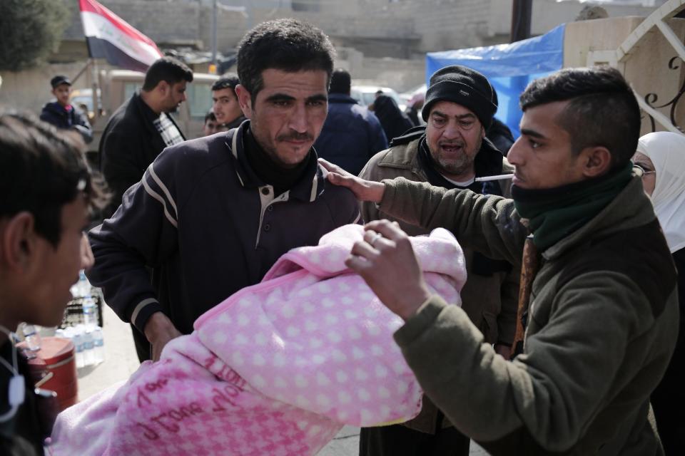 A man carries a wounded child to a hospital in the Zahra neighborhood of Mosul, Iraq, Tuesday, Feb. 14, 2017. Doctors in the small clinic in eastern Mosul say that since the operation to retake the city began months ago, they've only received intermittent deliveries of supplies. (AP Photo/Bram Janssen)