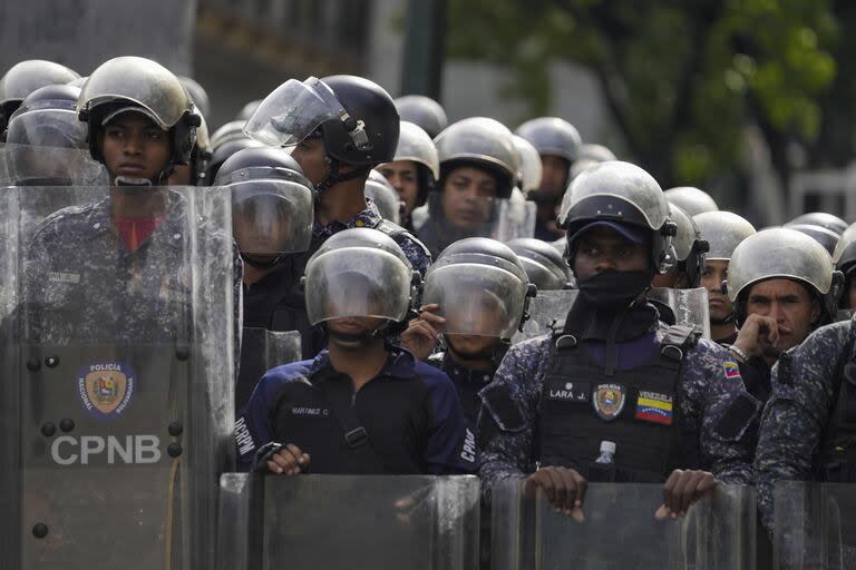 La policía bloquea a los manifestantes que se manifiestan contra los resultados oficiales de las elecciones que declaran la reelección del presidente Nicolás Maduro, el día después de la votación en Caracas.