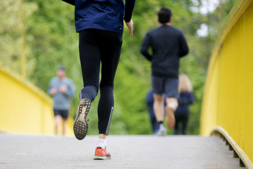 Jogger laufen im über eine Brücke. Wie weit sie dabei Tröpfchen verteilen, haben jetzt Forschende untersucht. Foto: Christoph Soeder / dpa 