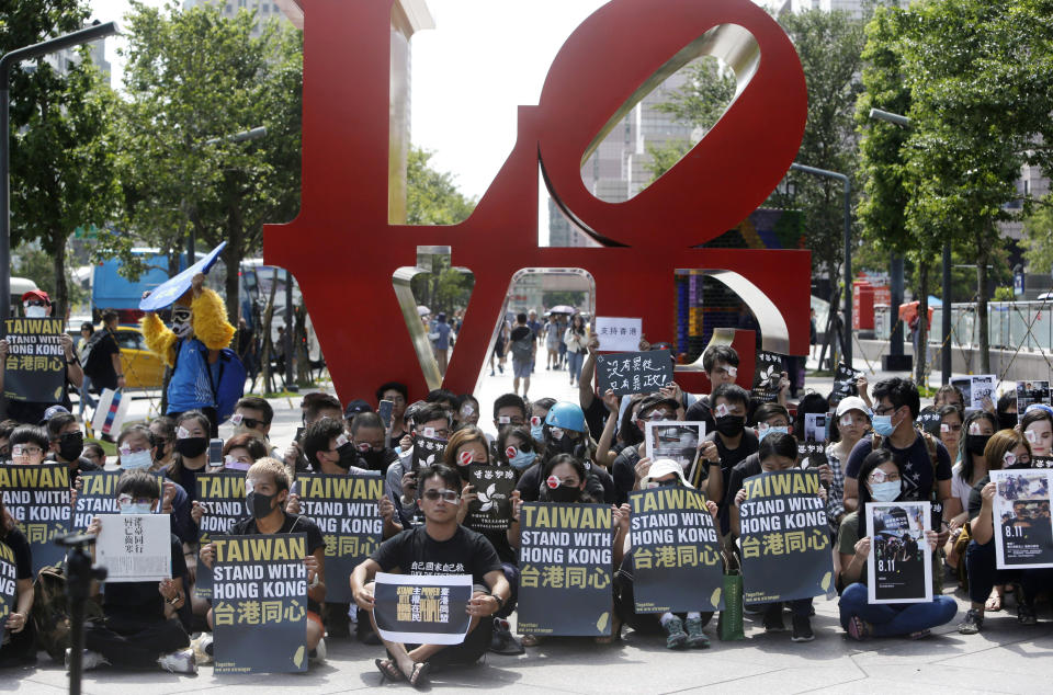 Hong Kong students living in Taiwan and Taiwanese supporters with their eyes covered in red-eyepatch, symbolizing a women reported to have had an eye ruptured by a beanbag round fired by police during clashes, hold slogans during a rally in Taipei, Taiwan, Saturday, Aug. 17, 2019. More than 100 people gathered to support Hong Kong's pro-democracy protesters. (AP Photo/Chiang Ying-ying)