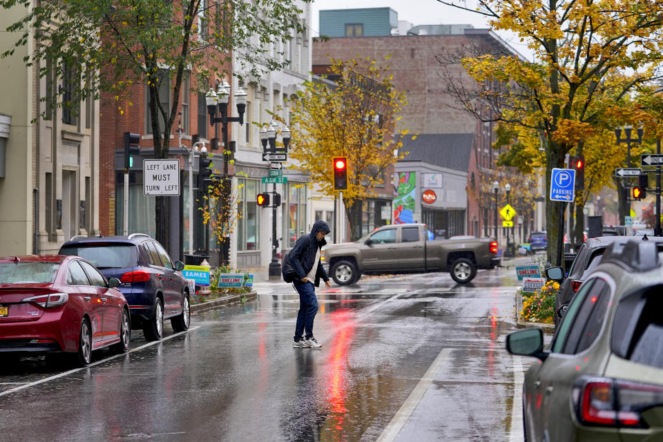 A man crosses the street, Monday, Oct. 30, 2023, in Lewiston, Maine. Residents of Lewiston returned to work Monday, the morning after coming together to mourn those lost in Maine's worst mass shooting. Investigators are still searching for a motive for the massacre that claimed 18 people at a bowling alley and a bar in Lewiston on Wednesday, Oct 25 as the community seeks a return to normalcy. (AP Photo/Matt York)