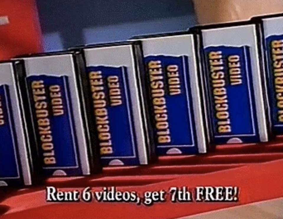 Six VHS tapes from Blockbuster Video lined up on a shelf. Text reads: "Rent 6 videos, get 7th FREE!"