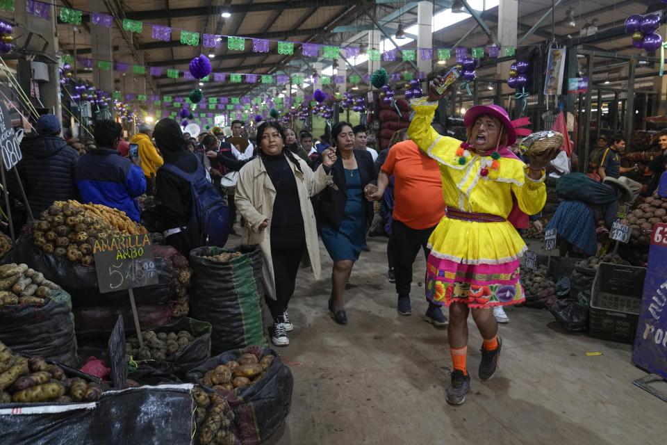 Un vendedor del mercado actúa, disfrazado, cerca de un puesto de venta de papas, celebrando el Día Internacional de la Papa, en las afueras de un mercado en Lima, Perú, el jueves 30 de mayo de 2024. (AP Foto/Martín Mejía)