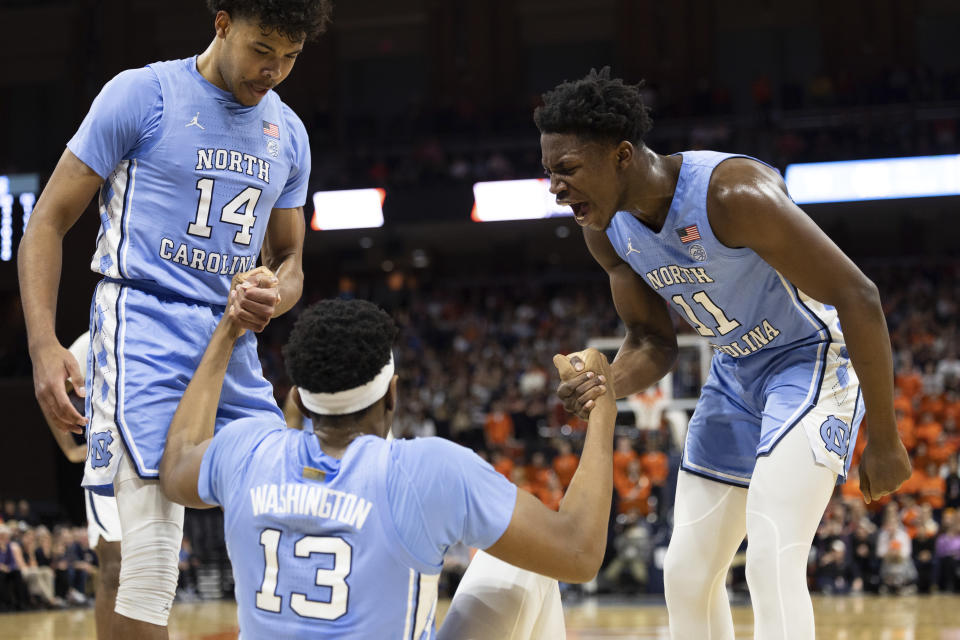 North Carolina's Donovan Johnson (14) and D'Marco Dunn (11) help Jalen Washington (13) up after a play against Virginia during the first half of an NCAA college basketball game in Charlottesville, Va., Tuesday, Jan. 10, 2023. (AP Photo/Mike Kropf)