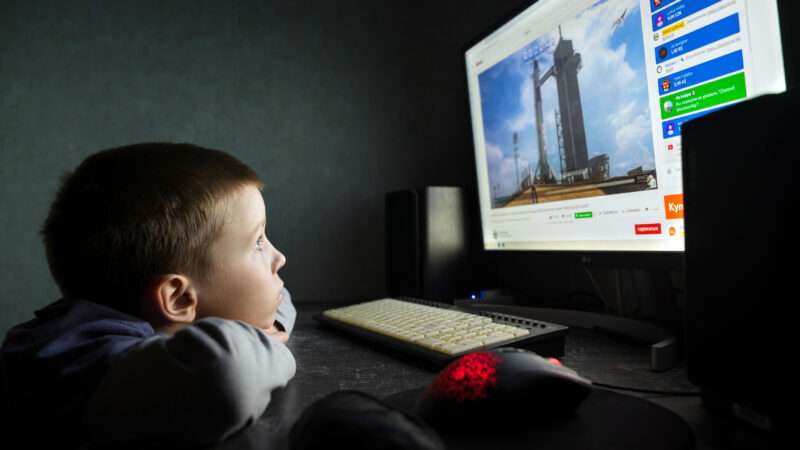 A young boy watches a SpaceX rocket launch on the Internet.