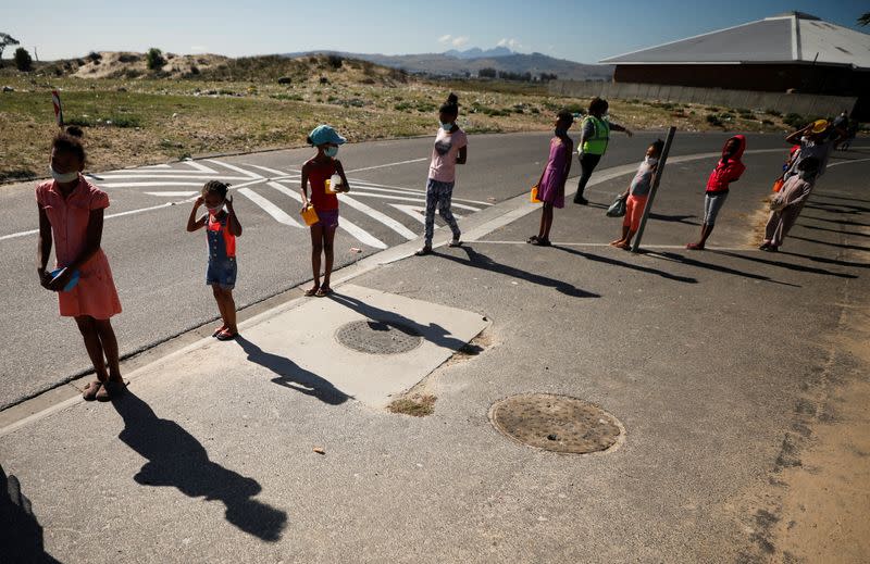 Children queue for food at a school feeding scheme during a nationwide lockdown aimed at limiting the spread of the coronavirus disease (COVID-19) in Blue Downs township near Cape Town