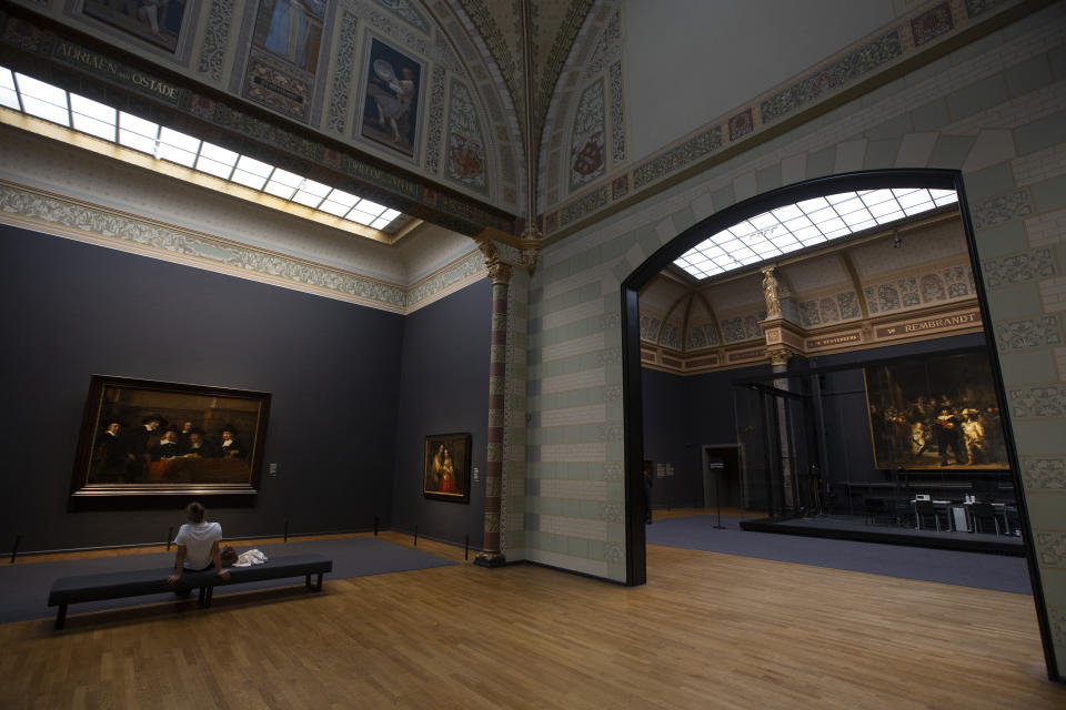 A limited amount of visitors admire paintings and Rembrandt's Night Watch, right, at the reopened Rijksmuseum in Amsterdam, Netherlands, Monday, June 1, 2020. The Dutch government took a major step to relax the coronavirus lockdown, with bars, restaurants, cinemas and museums reopening under strict conditions. (AP Photo/Peter Dejong)