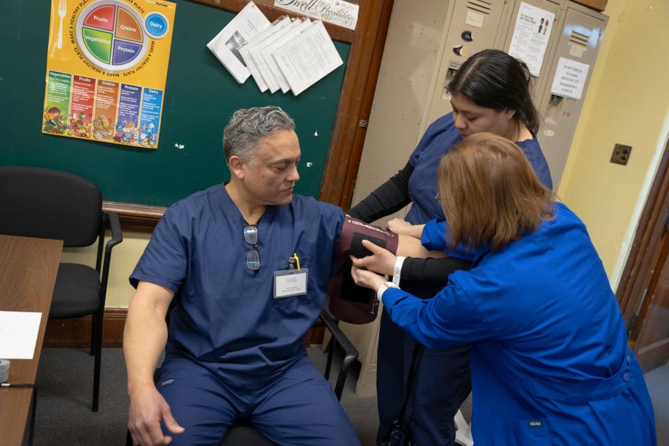Roberto Aguirre, seated, and Nicole Hernandez, right, get blood pressure instruction from Gienia Kocur, workforce learning facilitator for the CNA and medical assistant program at Genesis Center.