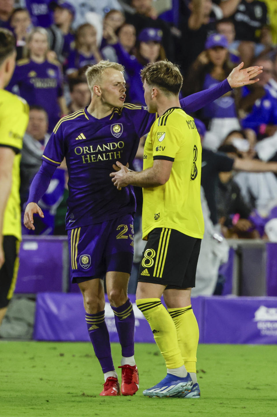 Orlando City midfielder Dagur Dan Þorhallsson, left, talks with Columbus Crew midfielder Aidan Morris during the second half of an MLS soccer playoff match, Saturday, Nov. 25, 2023, in Orlando, Fla. (AP Photo/Kevin Kolczynski)