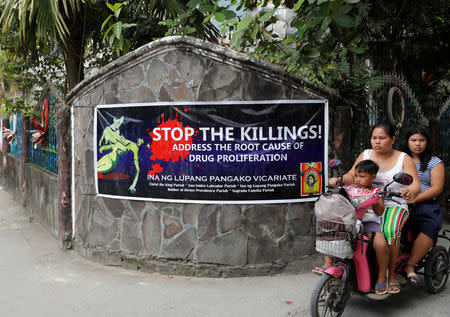 Residents ride a motorcycle past a banner opposing drug related killings along a street in Barangay Bagong Silangan, Quezon City, Metro Manila, in the Philippines November 22, 2017. REUTERS/Erik De Castro