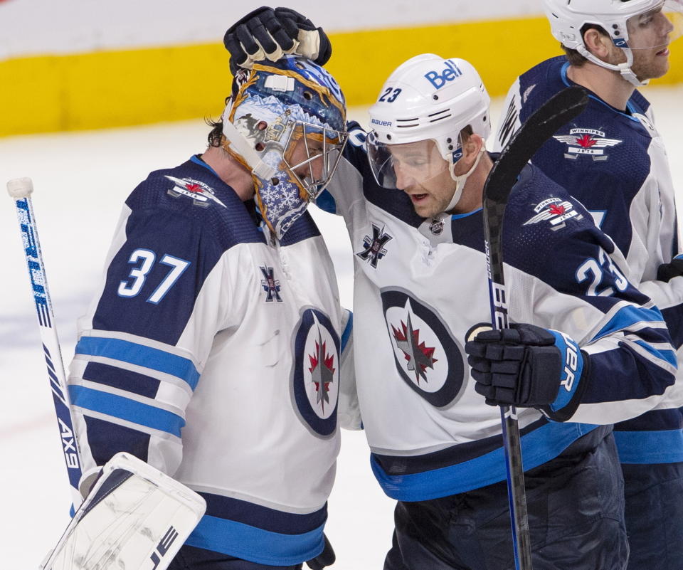 FILE - In this April 8, 2021, file photo, Winnipeg Jets goaltender Connor Hellebuyck (37) celebrates with Trevor Lewis (23) after the Jets defeated the Montreal Canadiens in an NHL hockey game in Montreal. The Winnipeg Jets are showing early signs of following the pattern of the 2012 Stanley Cup champion Los Angeles Kings. They have a stellar goaltender in Hellebuyck who, like Jonathan Quick nine years ago, is capable of stealing games. Lewis is the one common player who was on both teams (Ryan Remiorz/The Canadian Press via AP, File)