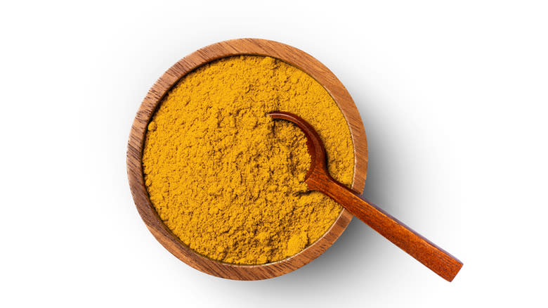 curry powder and spoon in wooden dish