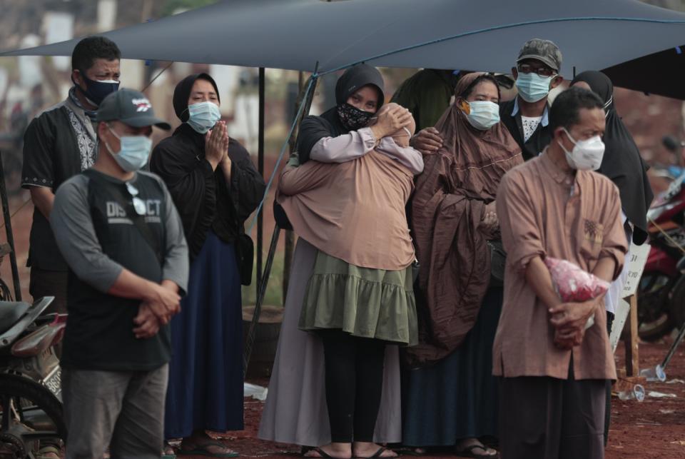 People react during the burial of a relative who died of COVID-19 complications Pondok Ranggon cemetery.