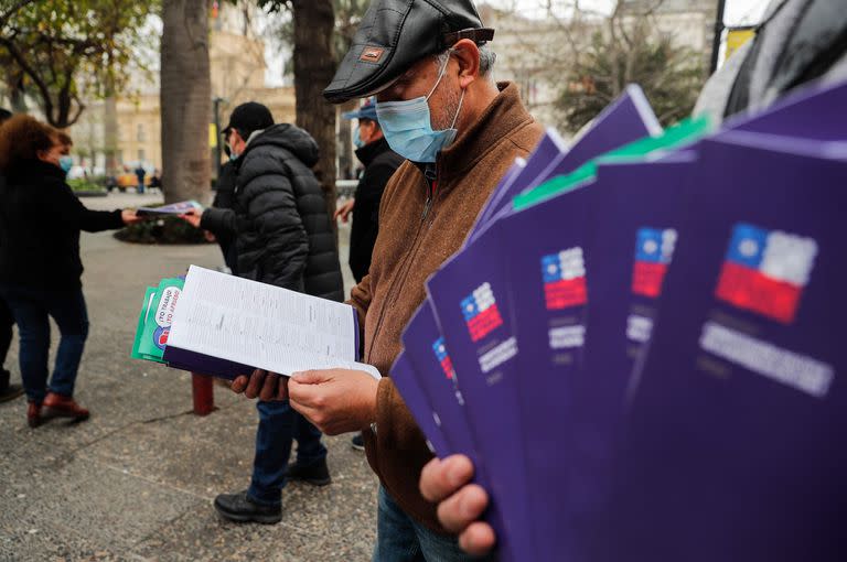 Un hombre lee el proyecto constitucional durante una marcha a favor del nuevo texto, en Santiago